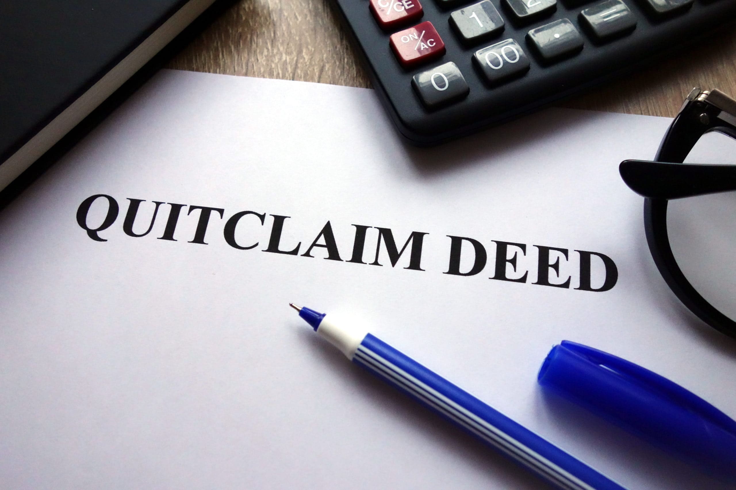 Paper with quitclaim deed on it surrounded by desk supplies