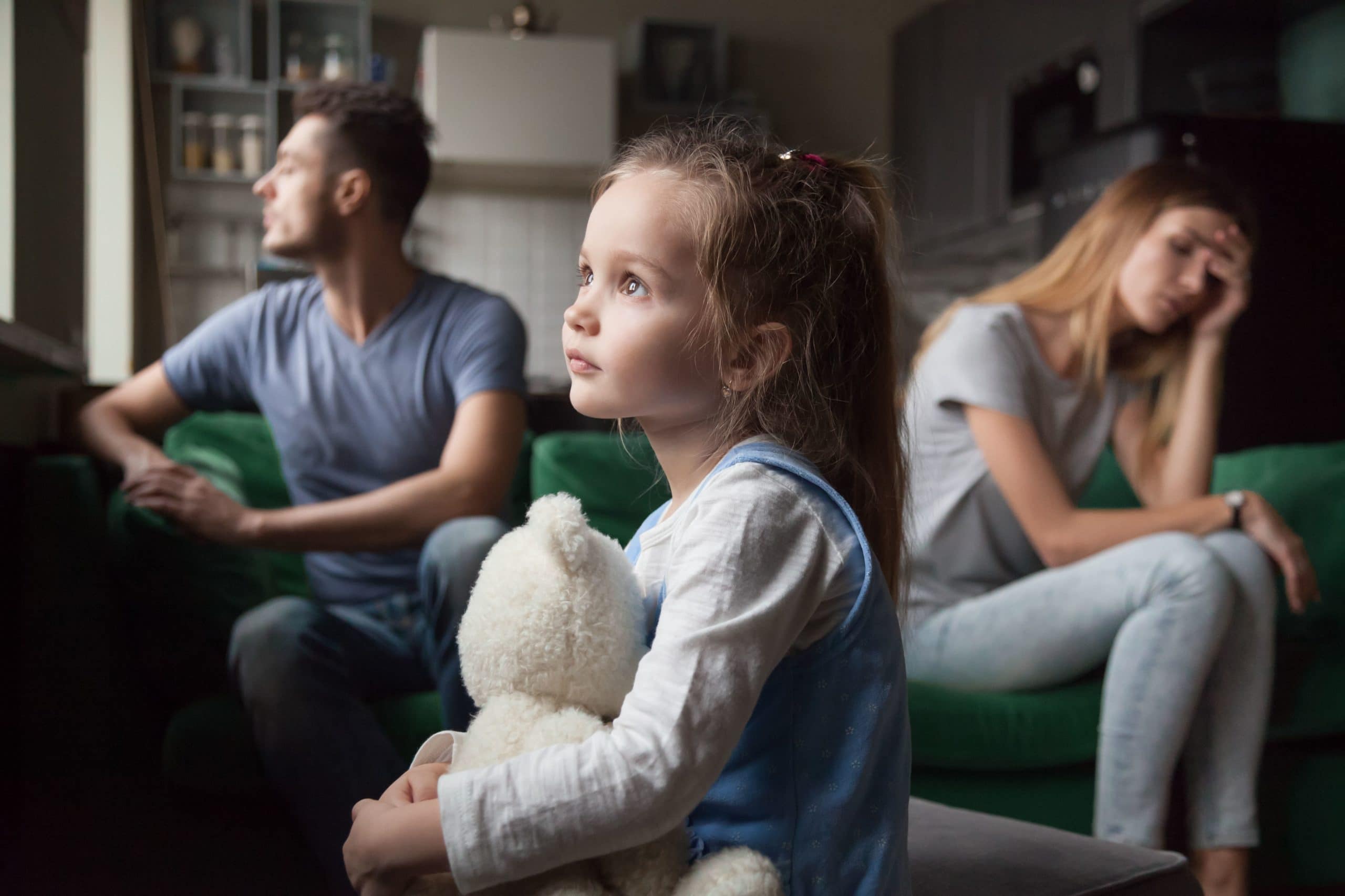 Child With Stuffed Animal Sitting Between Arguing Parents