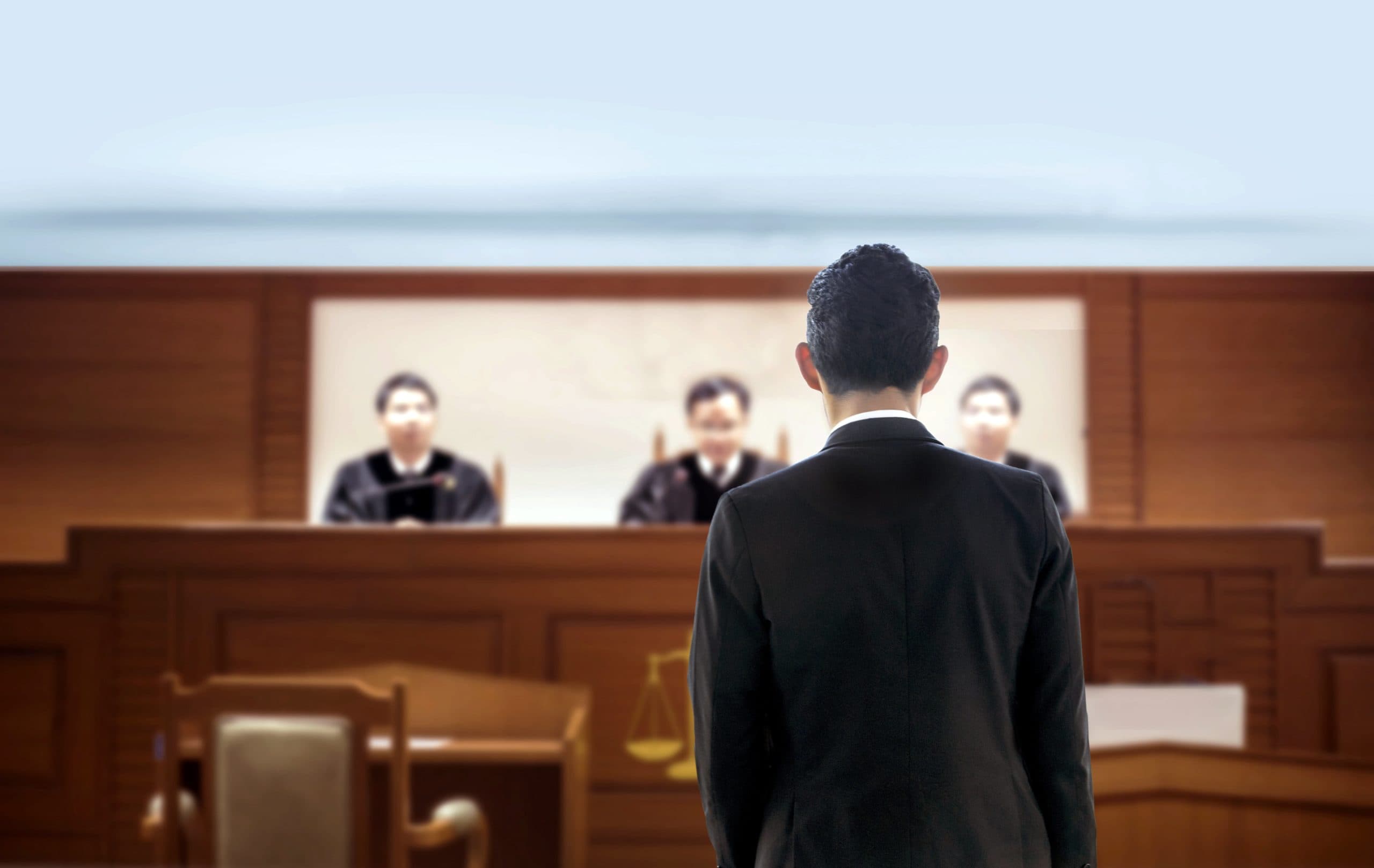 Man Standing Before Judges In Court Hearing