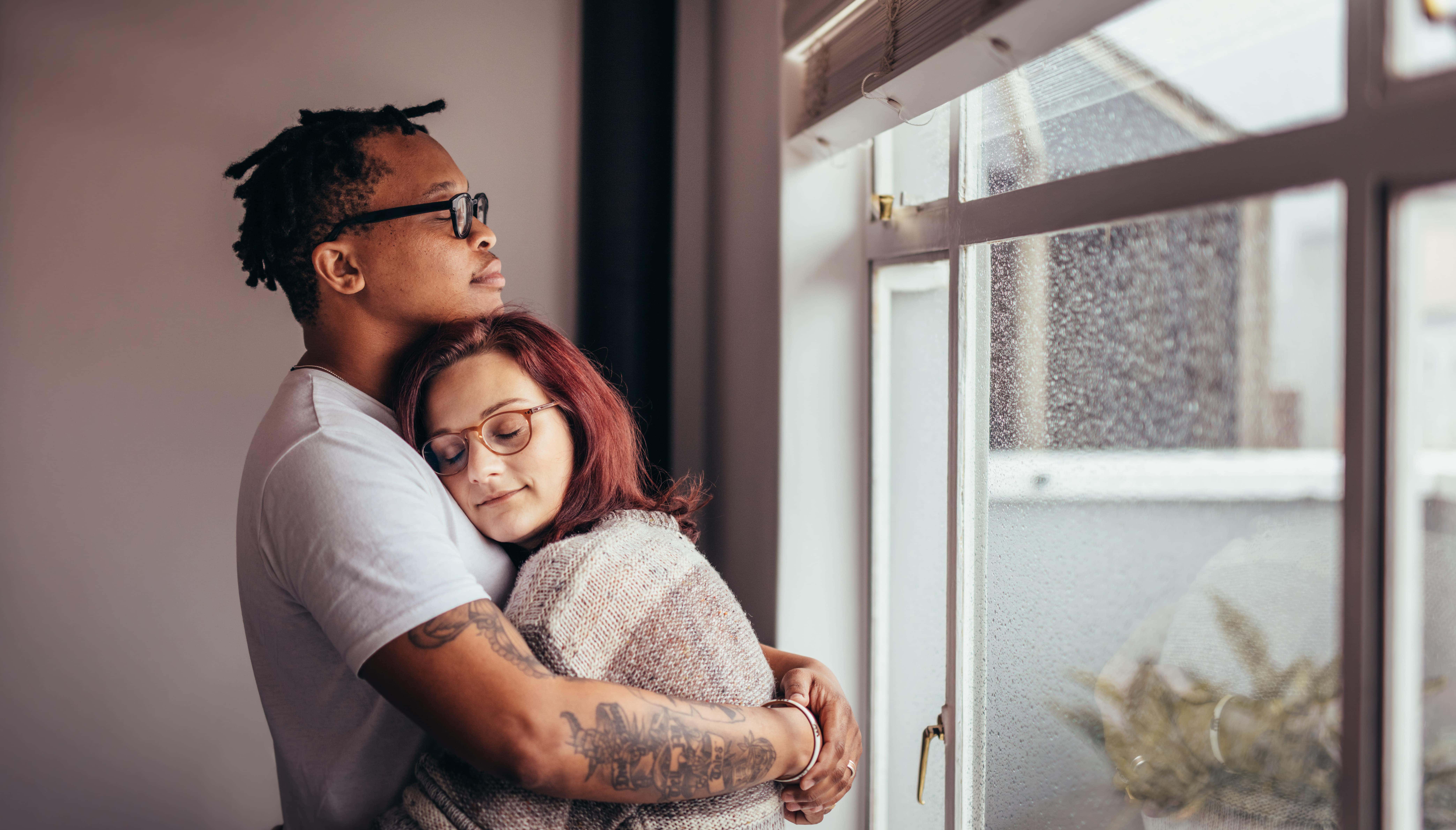 Interracial Couple Hugging By A Window