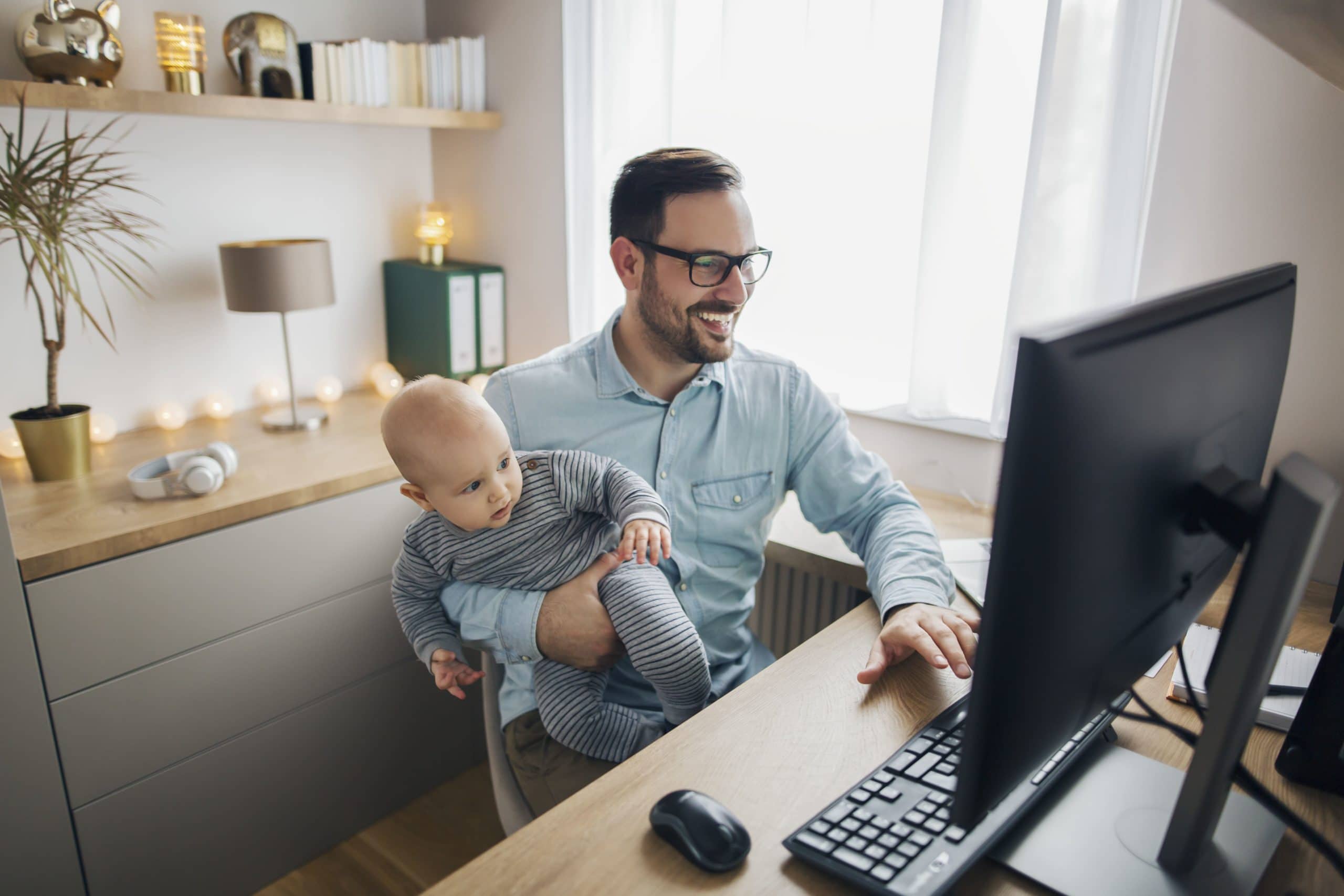 Father Holding Baby While Working On Computer