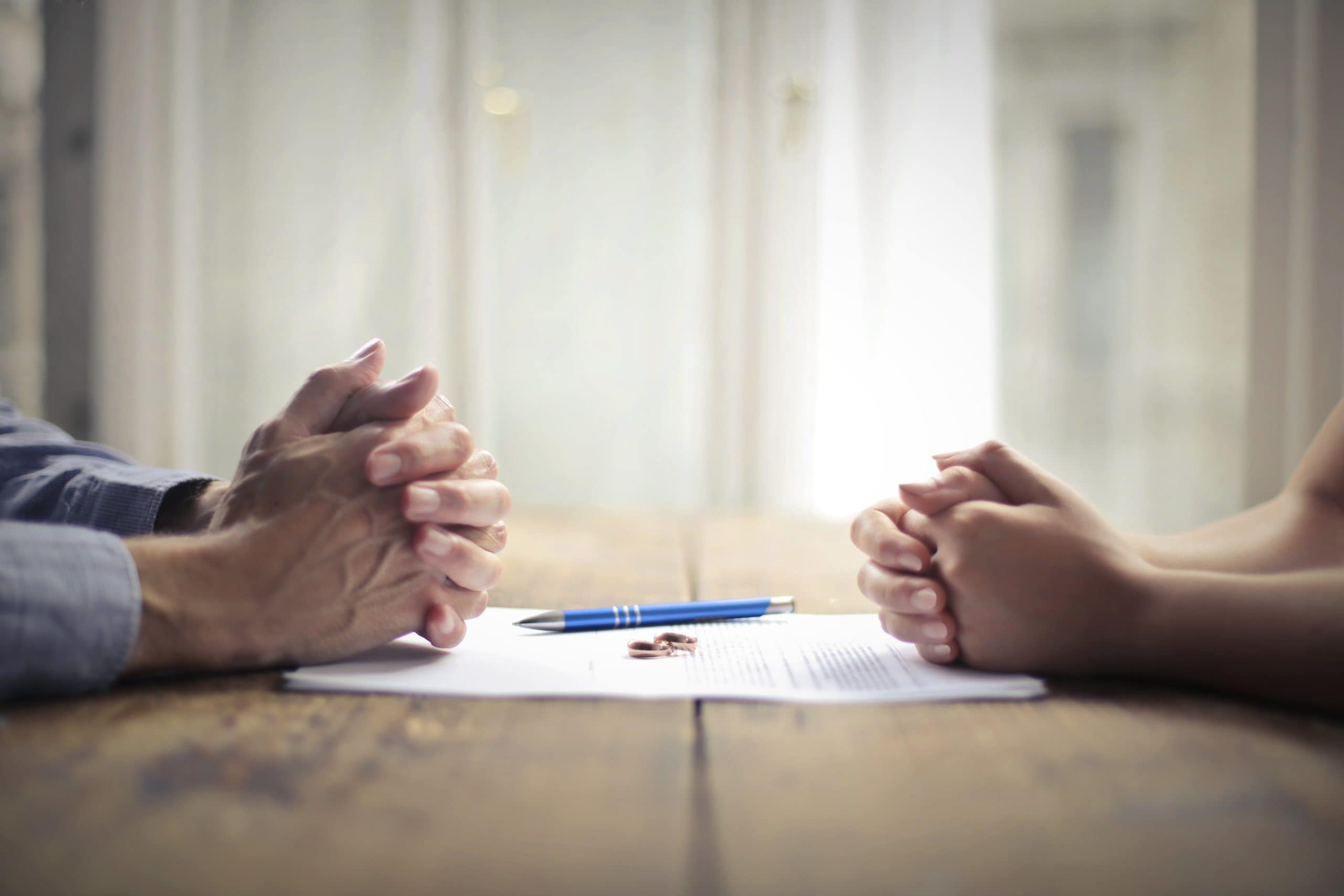Couple with clasped hands across a table negotiating divorce